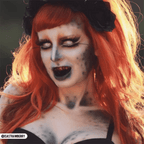 PRIMAL Sub Zero-inspired cosplayer with orange hair, pale blue makeup, white iris contacts, and black lips.