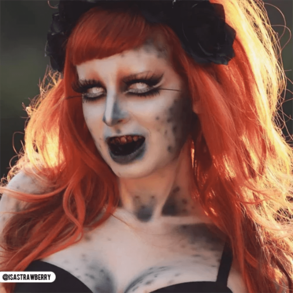 PRIMAL Sub Zero-inspired cosplayer with orange hair, pale blue makeup, white iris contacts, and black lips.
