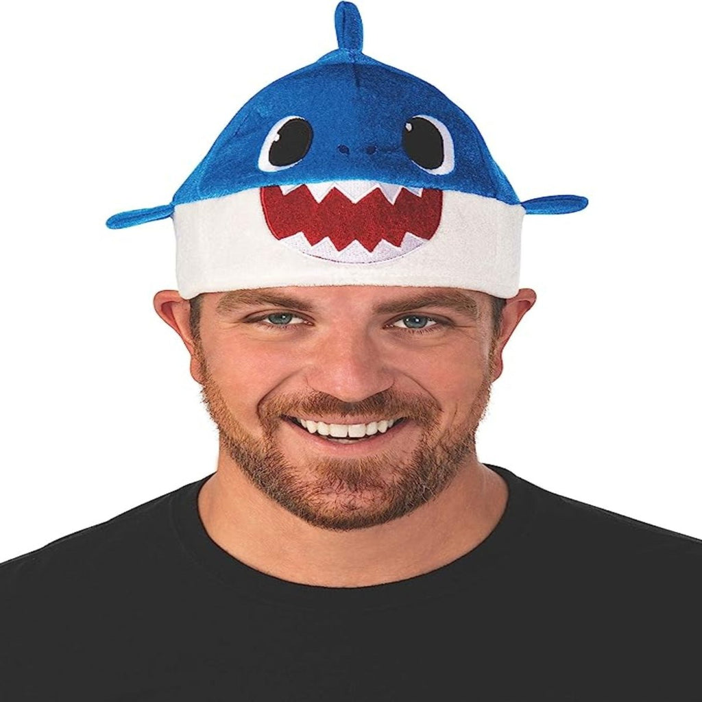 Man wearing Rubie's Baby Shark Hat with Original Song Sound Chip, blue shark design with white belly and red teeth.
